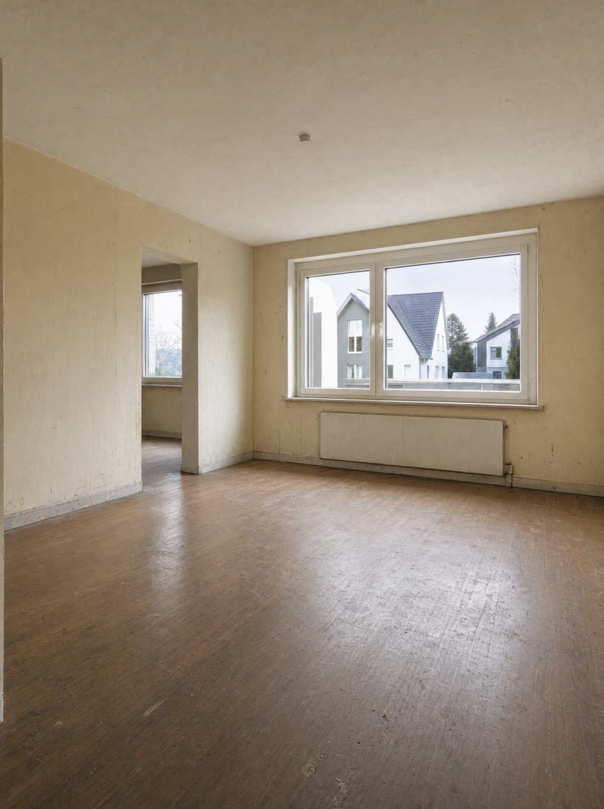 Wohnzimmer vor der Renovierung — vergilbte Wände, abgewohnter alter Boden
